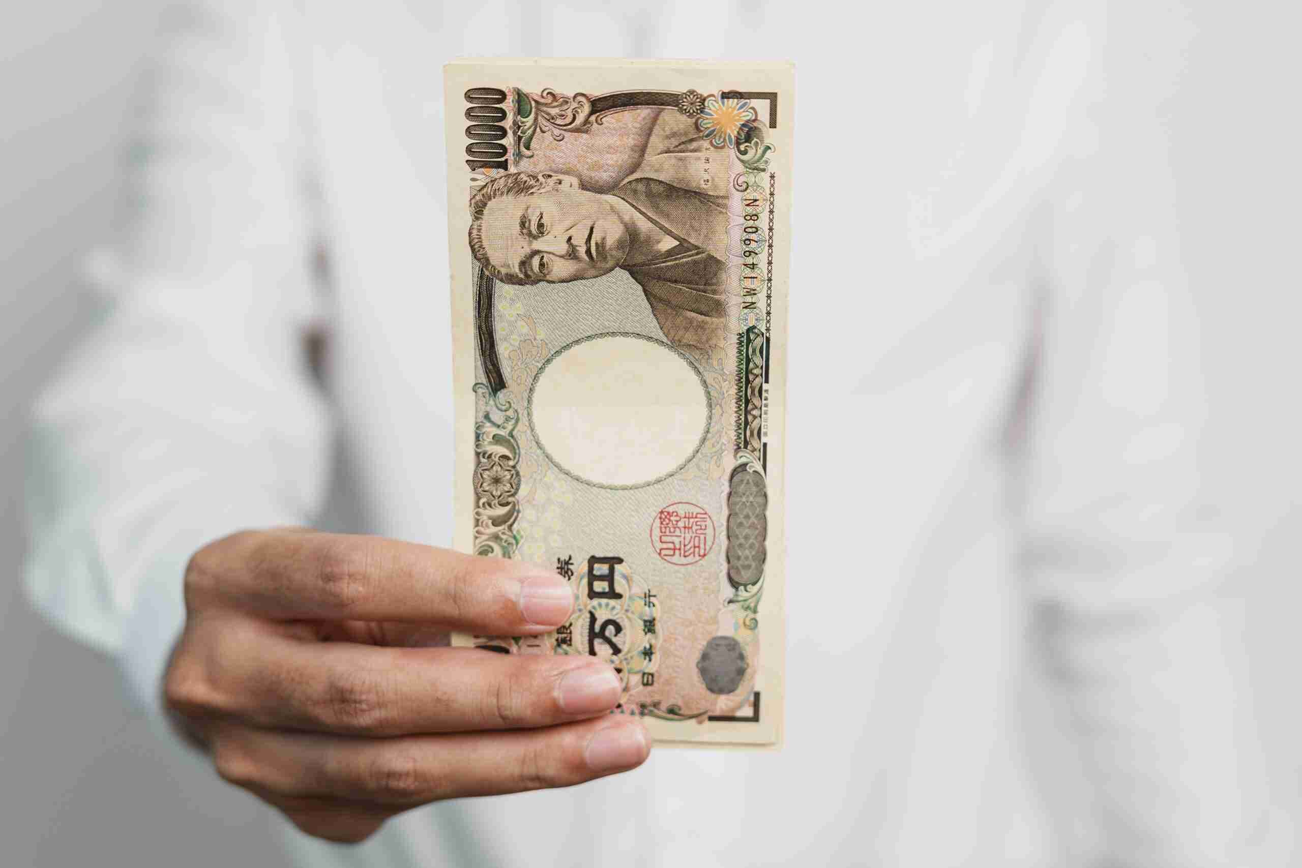 hand-holding-japanese-yen-banknote-stack-thousand-2023-11-27-05-34-28-utc-min-1-scaled-1_11zon